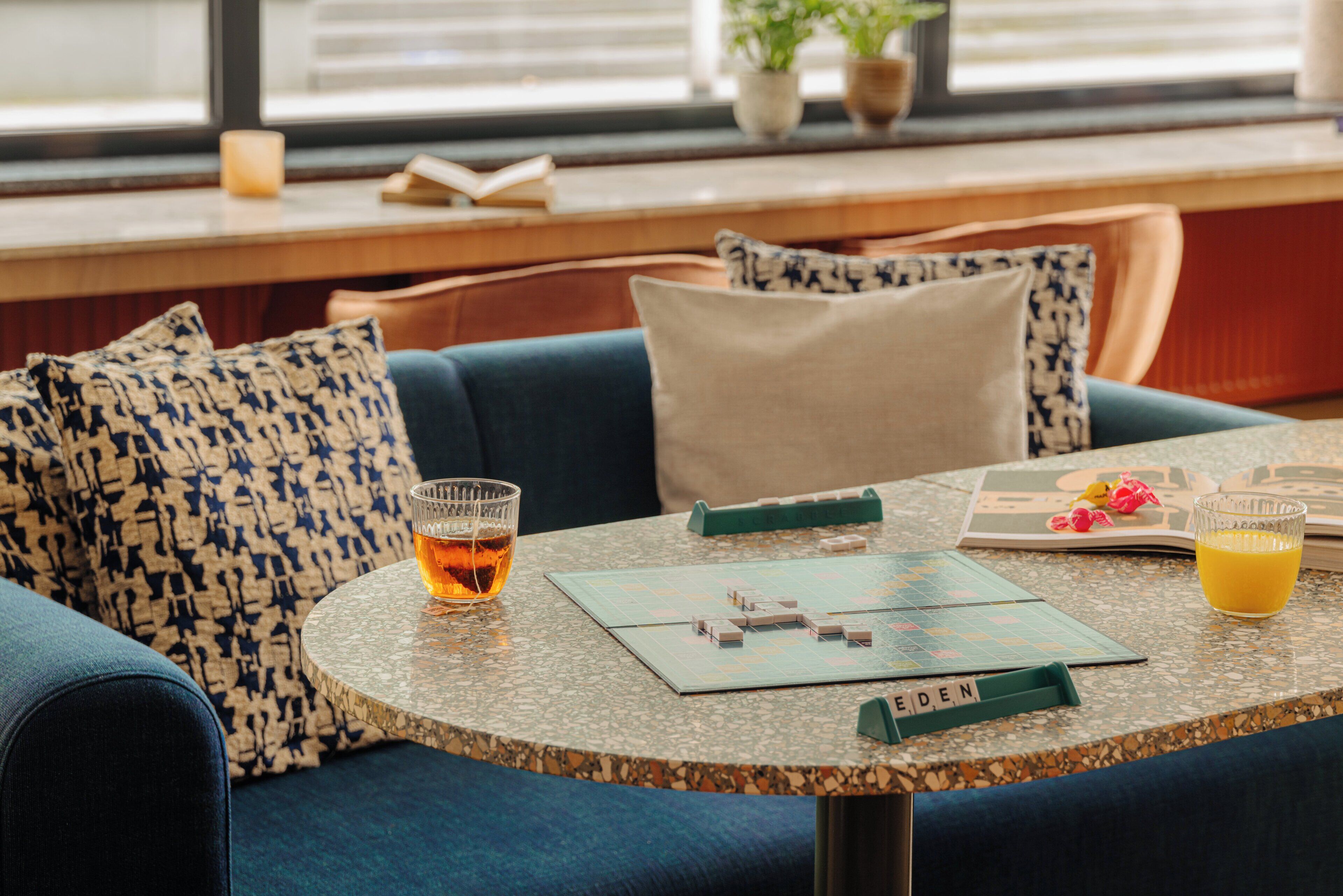 A cozy seating area with a round table, a board game, and two drinks.