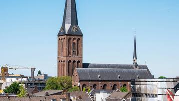A church with a tall spire and a modern building with a colorful facade in the foreground.