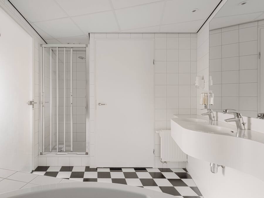 A modern bathroom with a checkered floor, a glass shower enclosure, and a double sink vanity.