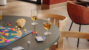 Una mesa con un juego de mesa, dos copas de vino, un bol de palomitas y cartas.
