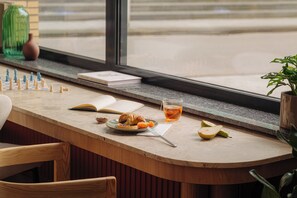 A breakfast table with a chessboard, a book, a croissant, a plate with fruit, and a glass of tea. - Leonardo Hotel Hengelo City Center (Hengelo)