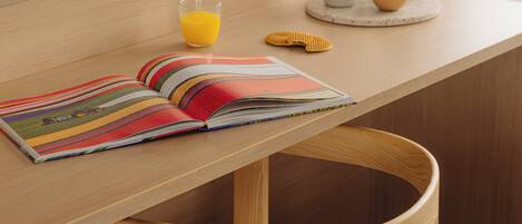 A wooden table with a book, a glass of orange juice, and a small bowl.