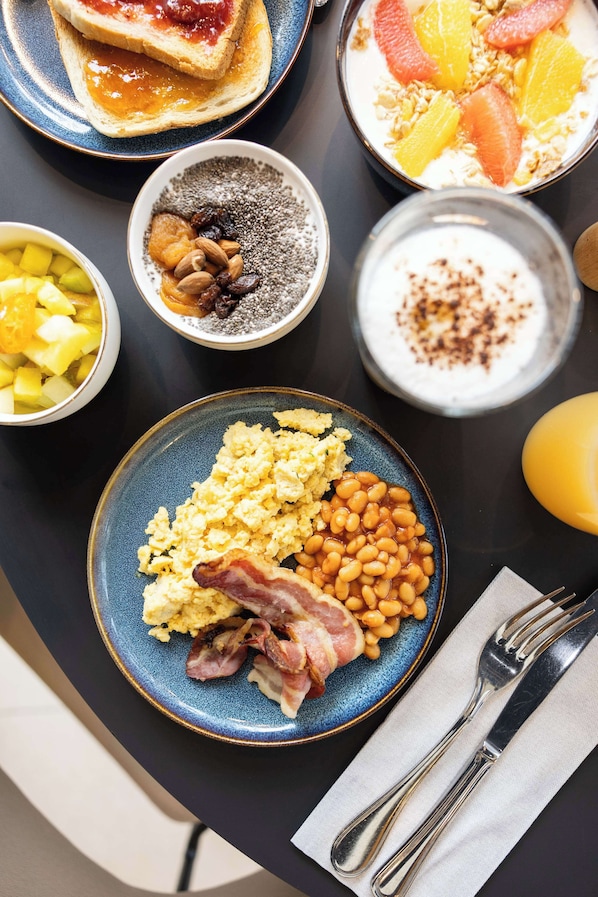 A breakfast spread with toast, cereal, fruit, and eggs on a table.