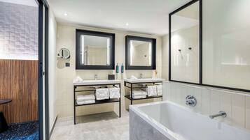 Un baño moderno con dos lavamanos, una bañera grande y un espejo sobre cada lavamanos.