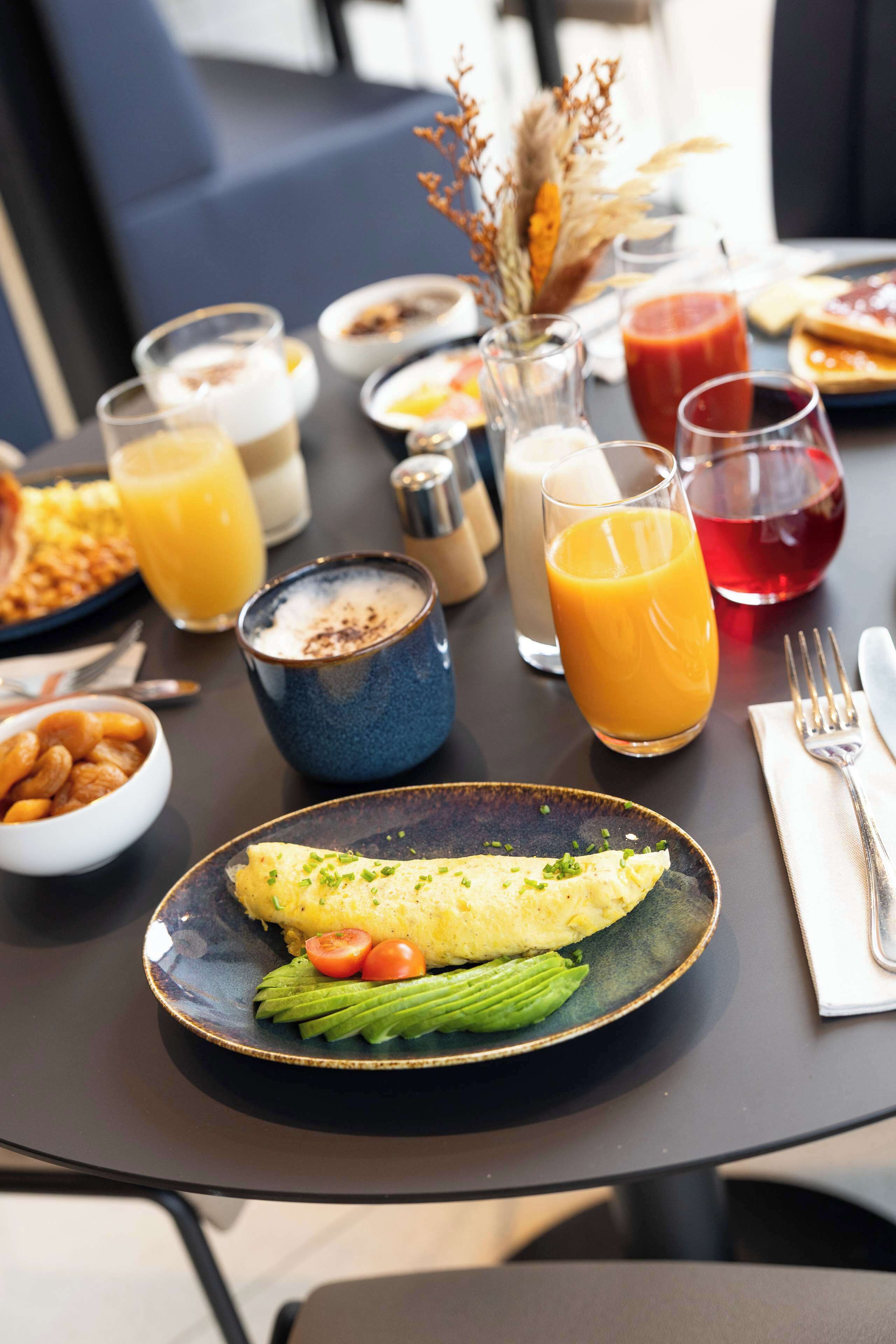 A breakfast setting with a plate of eggs, vegetables, and a glass of orange juice.