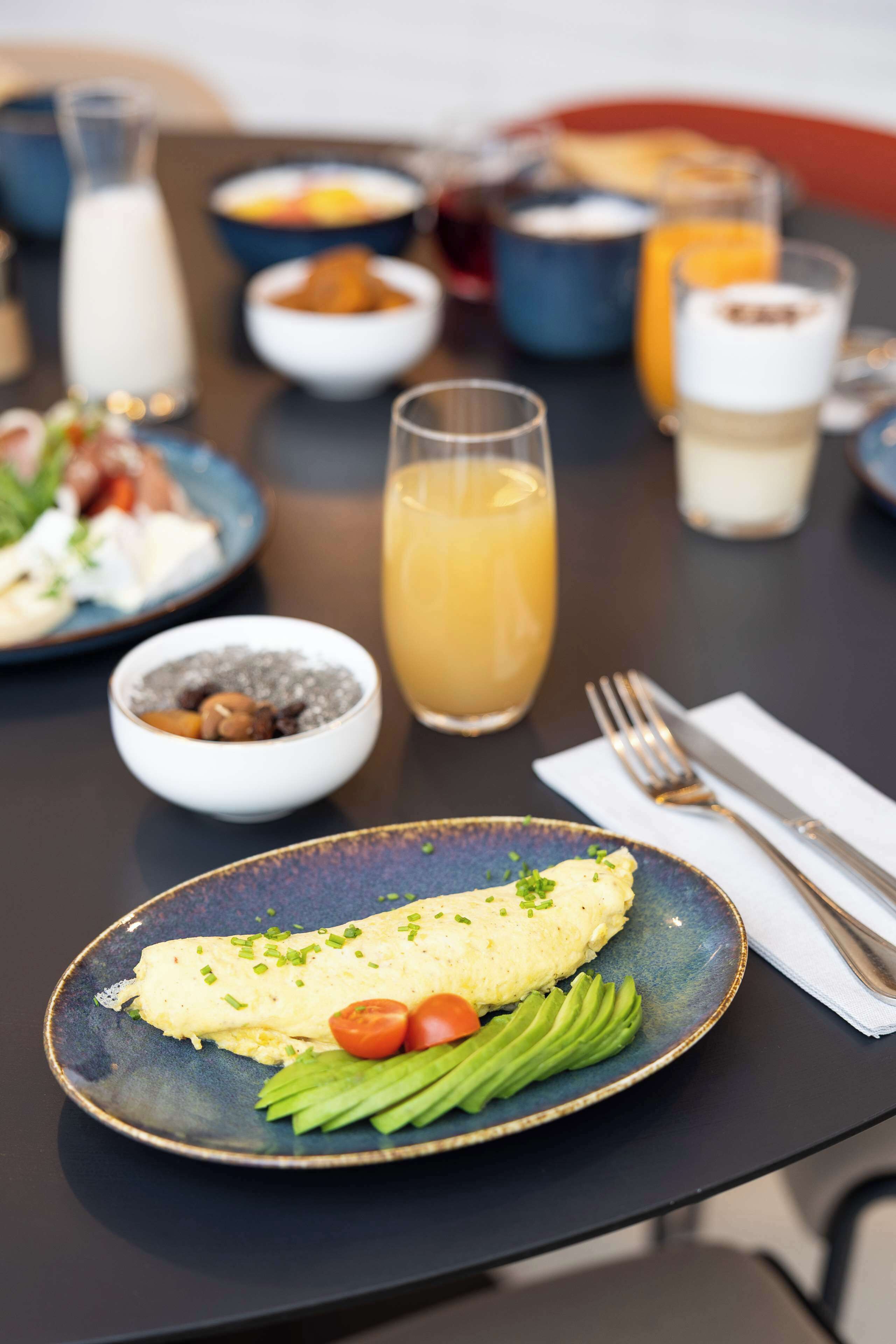 A breakfast setting with a plate of food, a glass of orange juice, and a bowl of nuts.