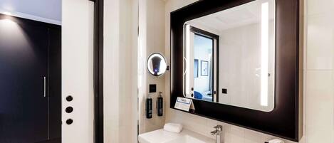 A modern bathroom with a large mirror, a sink, and a door with a handle.