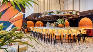 A bar area with a curved counter, multiple stools, and a variety of bottles on display.