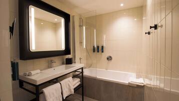 A modern bathroom with a large mirror, a sink, a bathtub, and a shower.