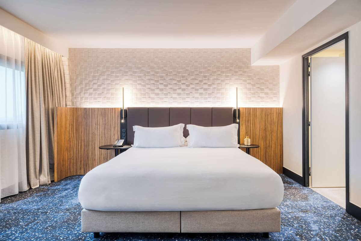 Une chambre d’hôtel avec un grand lit, un mur décoratif en bois et un plafond à texture.