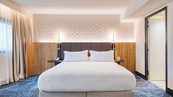 Habitación de hotel con una cama grande, un revestimiento de pared de madera y un techo texturizado.