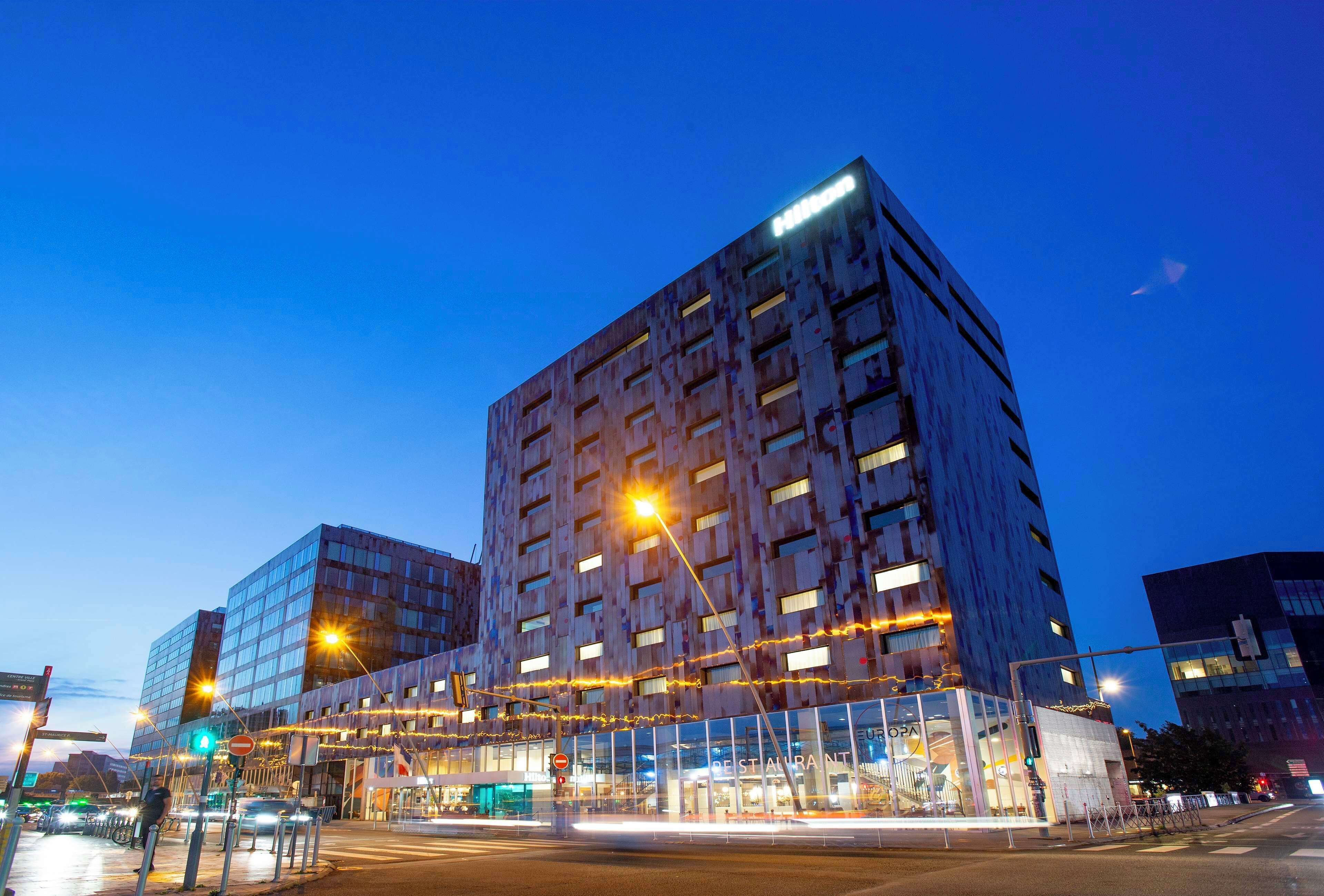 Un edificio moderno con facciata in vetro, un ristorante e un percorso pedonale.