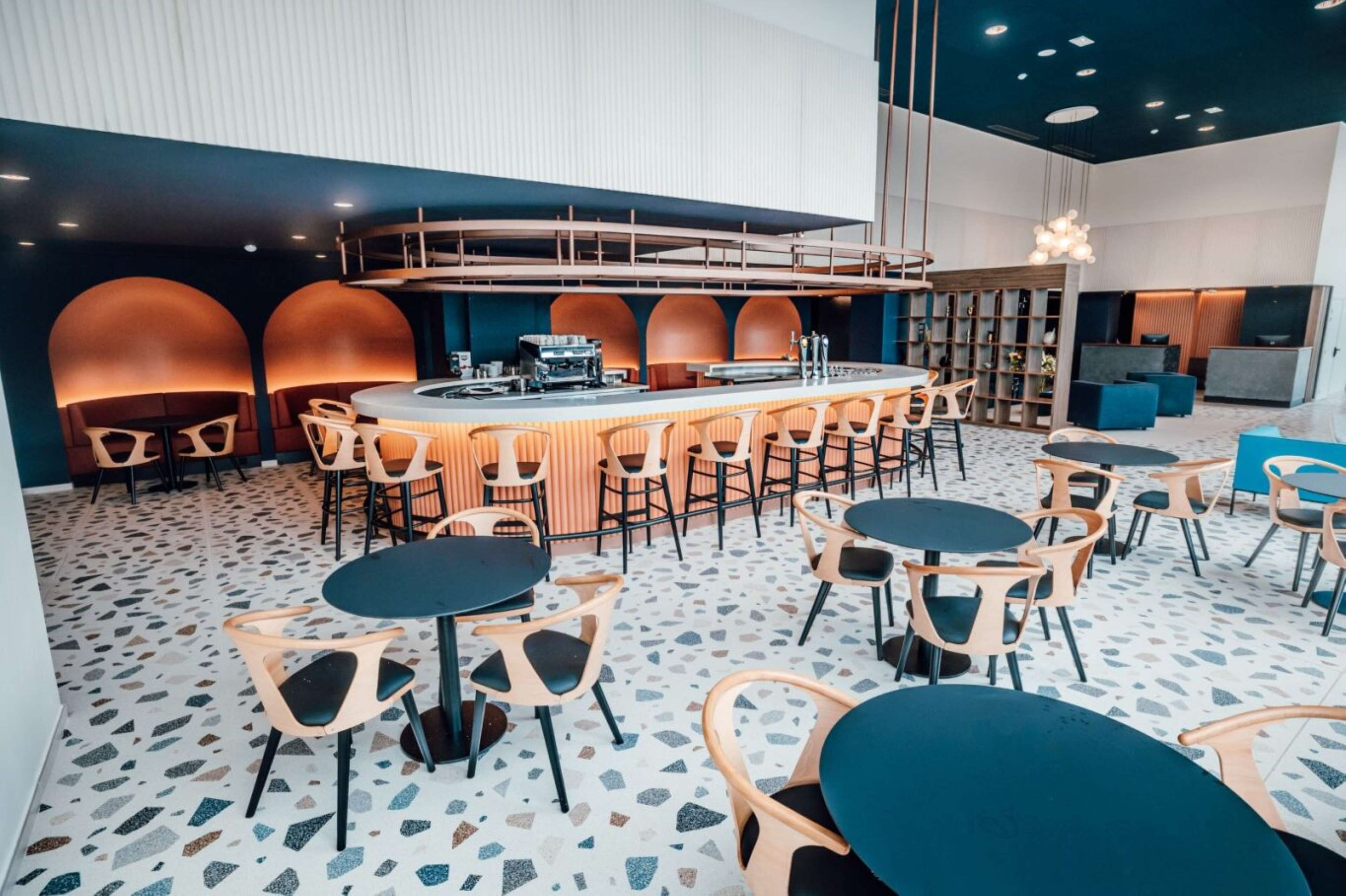 Un bar moderno con una barra central, diversas opciones de asientos y un suelo estampado.