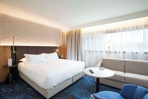 Relax in a spacious room with a large bed, sofa, and small table for dining or unwinding.