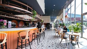 Un espace bar moderne doté d’un comptoir incurvé, de tabourets de bar et d’une variété d’aménagements, notamment des tables et des chaises rondes.