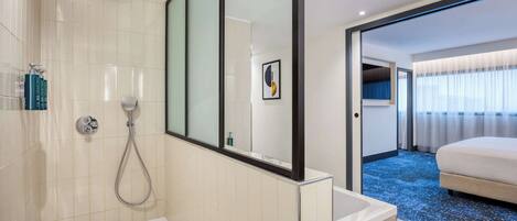 Un baño moderno con bañera, ducha y un espejo grande.