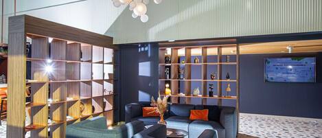 En moderne lobby med et siddeområde, en træbogreol og en opslagstavle på væggen.
