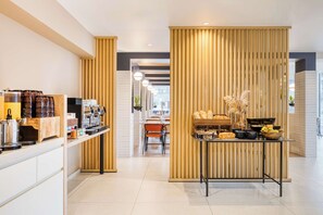Café area with a long counter and seating, offering a selection of coffee and baked goods.