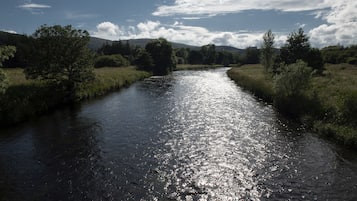 Un río serpenteando por un paisaje natural con árboles y colinas al fondo.