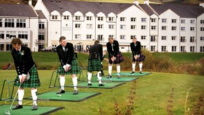 A group of men in kilts on a golf course with a hotel in the background. - Macdonald Cardrona Hotel, Golf & Spa (Peebles)