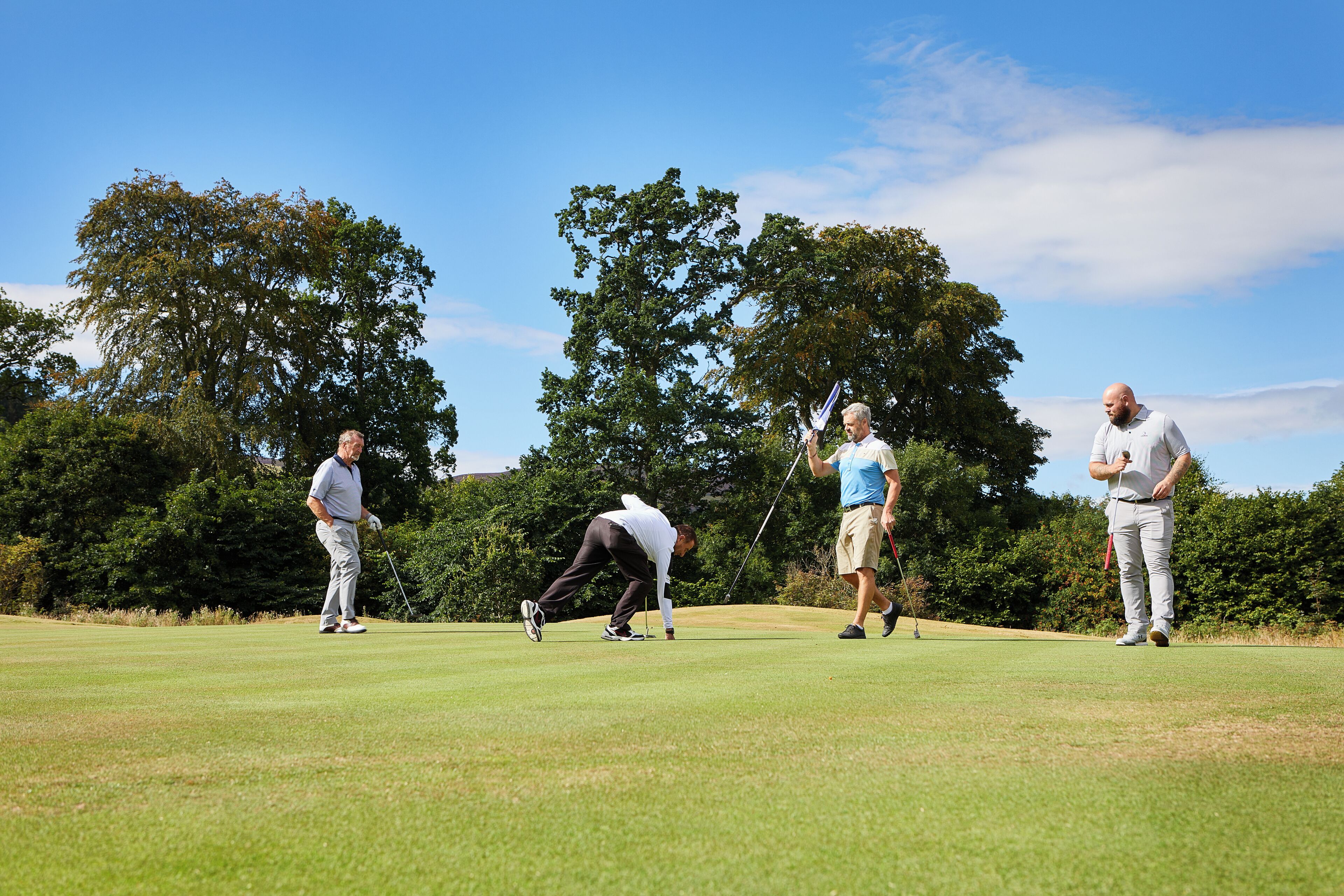 A golf course with four people playing.