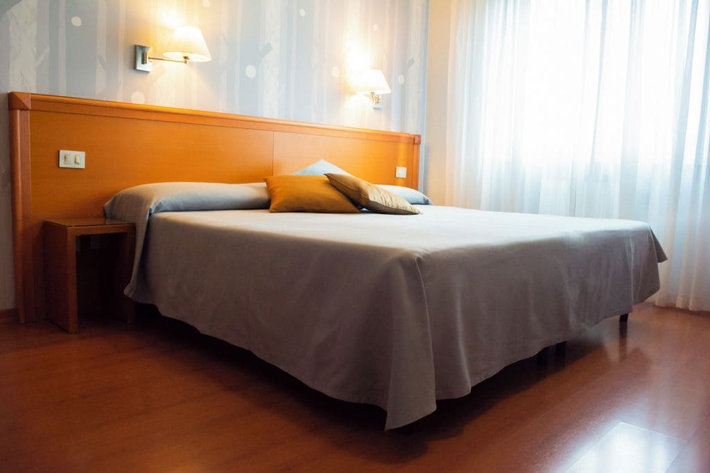 Ein Hotelzimmer mit einem großen Bett, einem Holz-Kopfteil, zwei Nachttischlampen und einem Nachttisch.