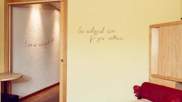 Ein Zimmer mit Holztür, einer Wand mit Wellness-Aufschrift und einem roten Kissen auf einem Bett.