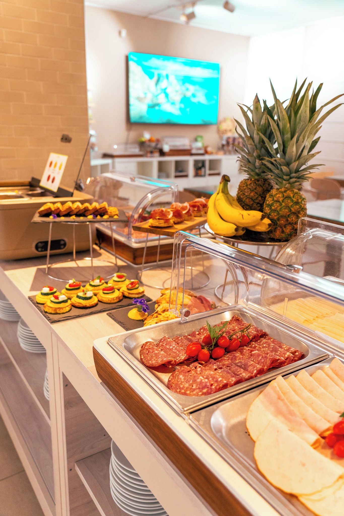 Un buffet proposant une variété de plats, notamment des viandes en tranches, des fruits et des pâtisseries.