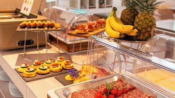 Un buffet proposant une variété de plats, notamment des viandes en tranches, des fruits et des pâtisseries.