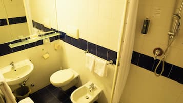Een kleine badkamer met een wastafel, toilet, toiletbril en een douchehoek.