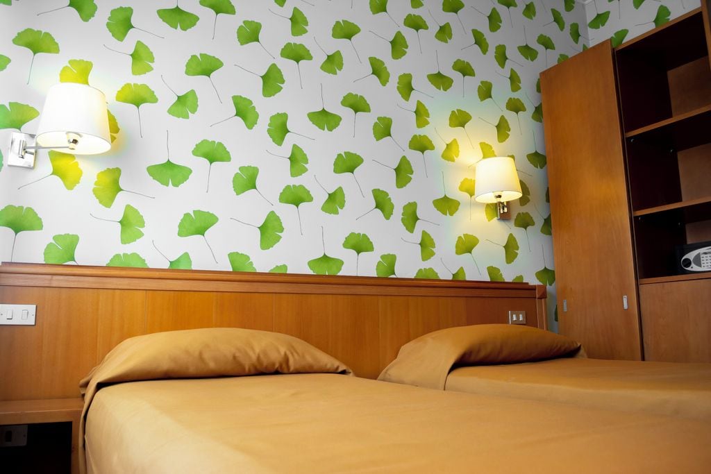 Una camera d'albergo con un letto, due lampade a parete e un armadio.
