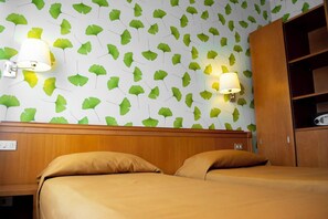 Een hotelkamer met een bed, twee wandlampen en een kledingkast.