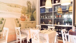 A restaurant interior with white tables and chairs, a wine display, and a mural on the wall. - eco Hotel Milano & BioRiso Restaurant (Milan)