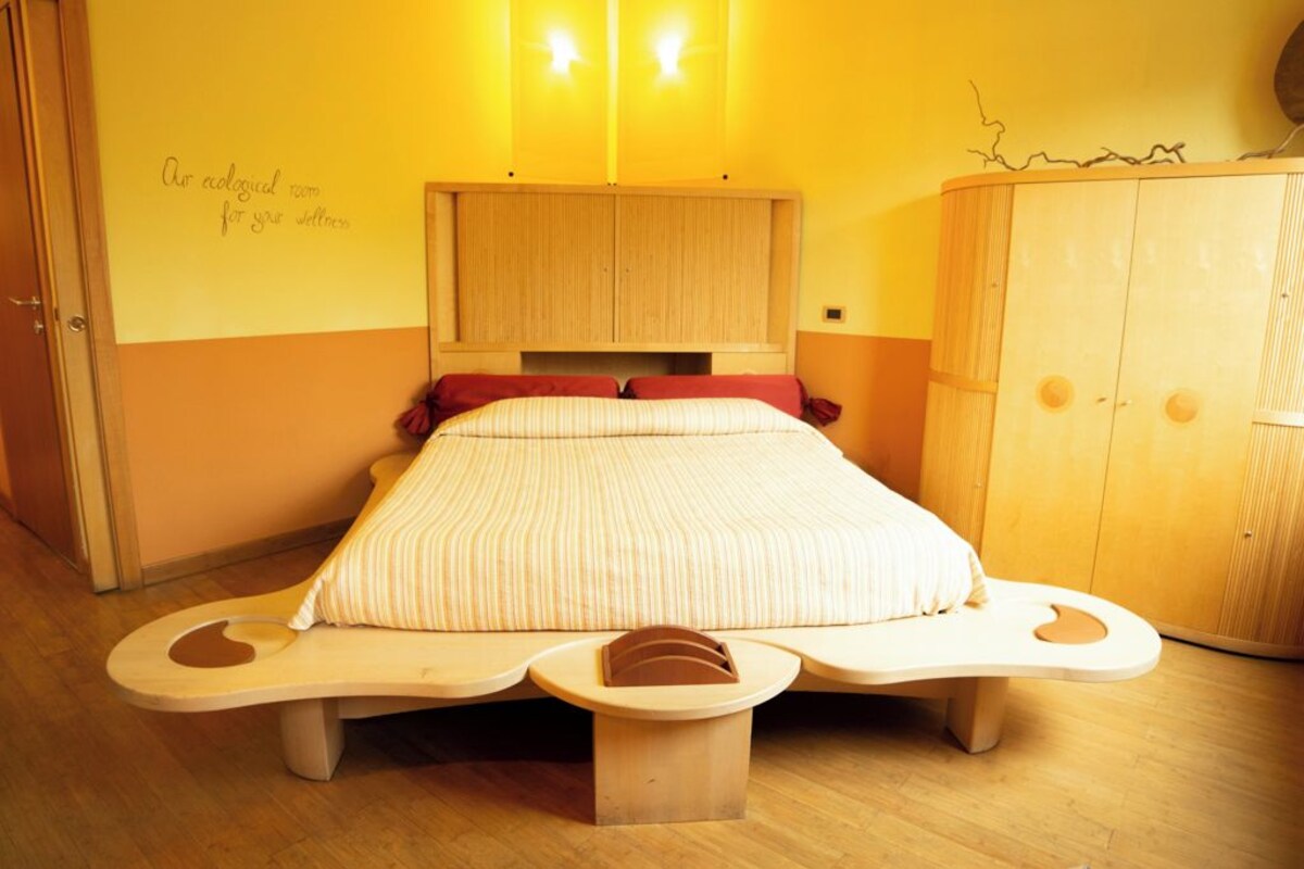 Una habitación con una cama, un armario de madera y una pared con un mensaje.