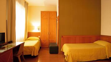A hotel room with two beds, a desk, a chair, a television, and a wardrobe.