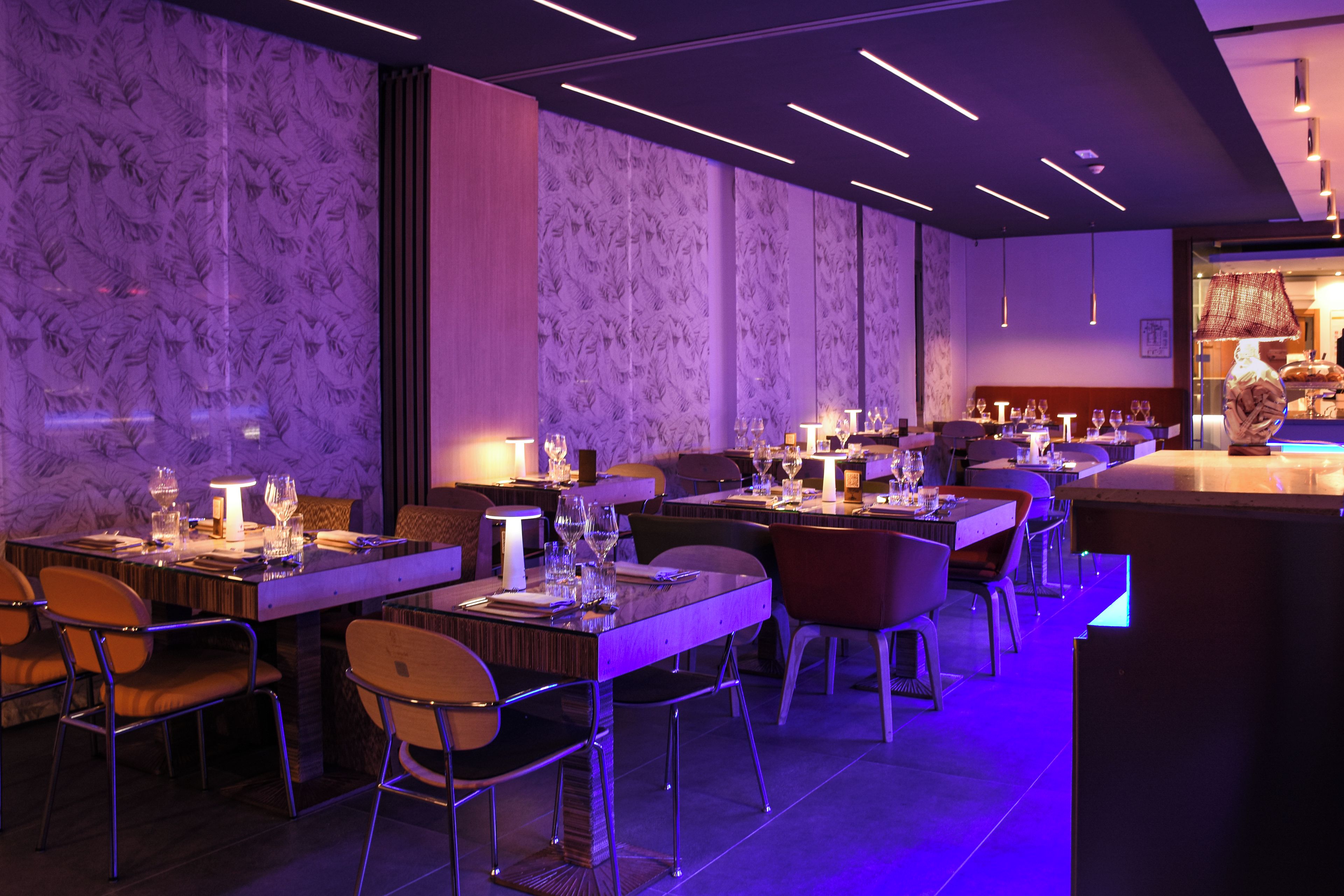 Een restaurantinterieur met gedekte tafels, stoelen en een bar.