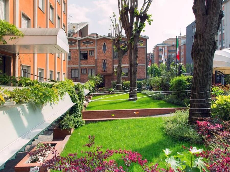 Um pátio com gramado, edifícios de tijolo e uma árvore.