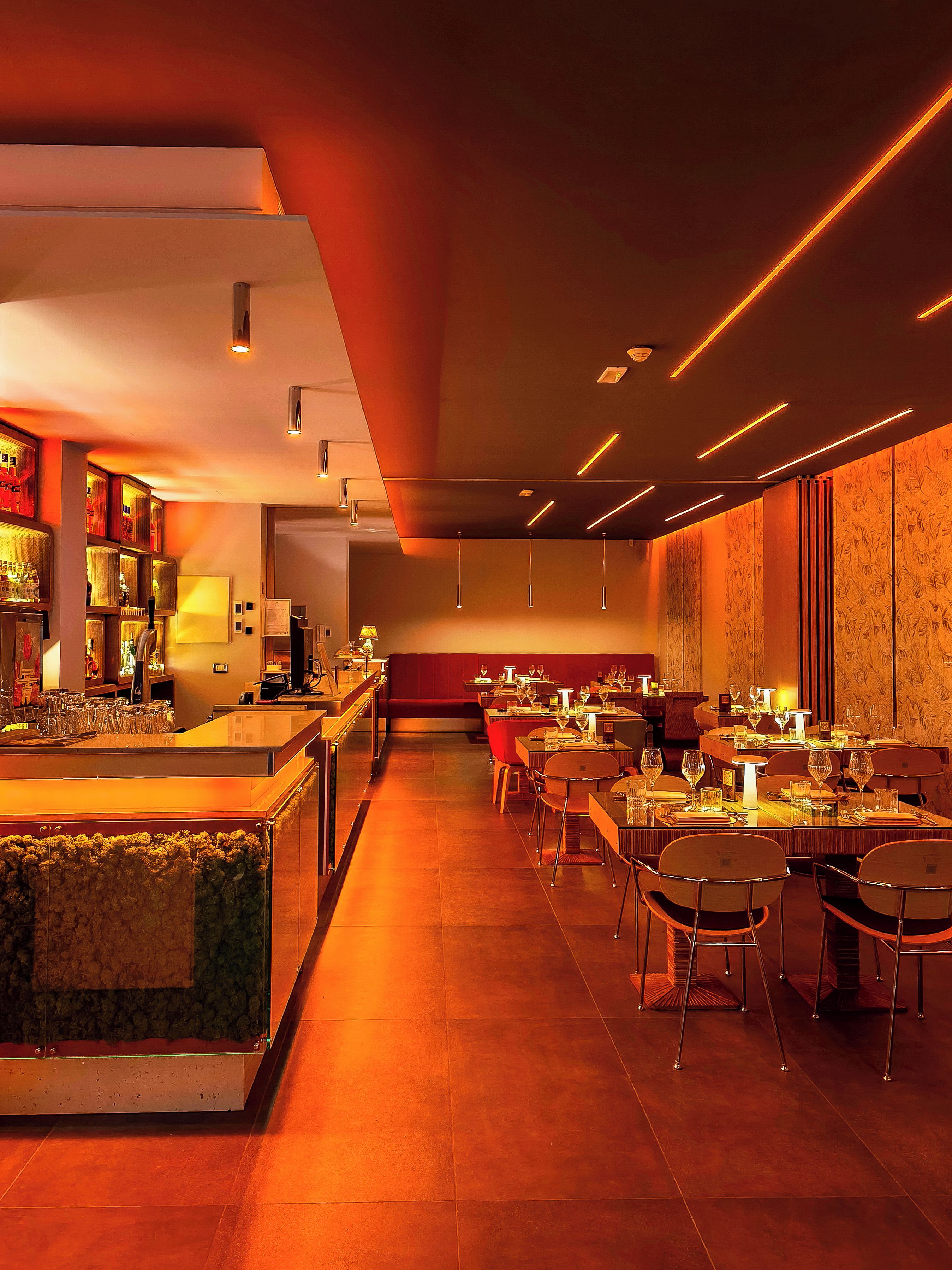 A restaurant with a bar area, multiple dining tables, and chairs.