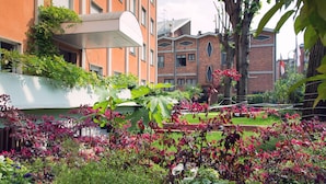A garden with various plants and flowers, a brick building, and a white structure with a sloped roof. - eco Hotel Milano & BioRiso Restaurant (Milan)