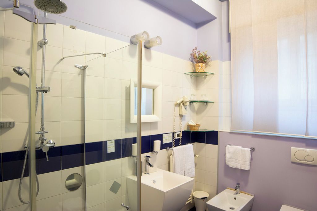 Een badkamer met een douchecabine van glas, een witte wastafel en een toilet.
