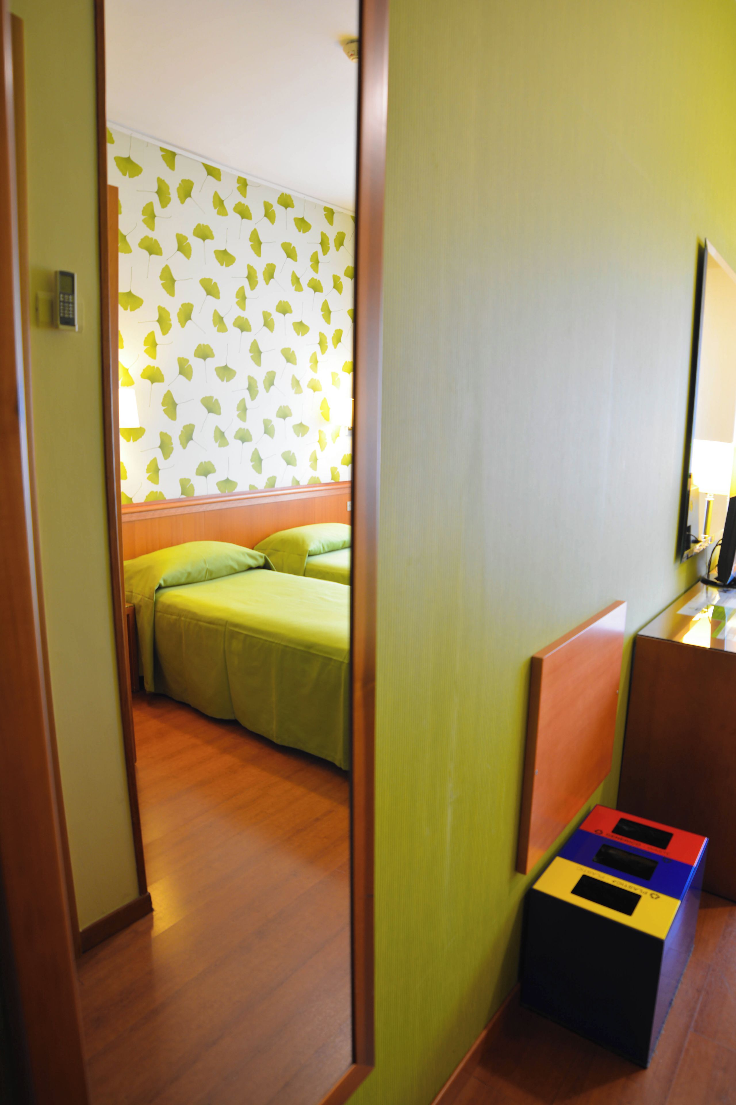 Una camera d'albergo con un letto, un comodino e uno specchio.