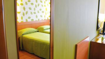 Una camera d'albergo con un letto, un comodino e uno specchio.