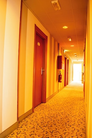 A hotel corridor with doors on both sides, a fire extinguisher mounted on the wall, and a carpeted floor. - eco Hotel Milano & BioRiso Restaurant (Milan)