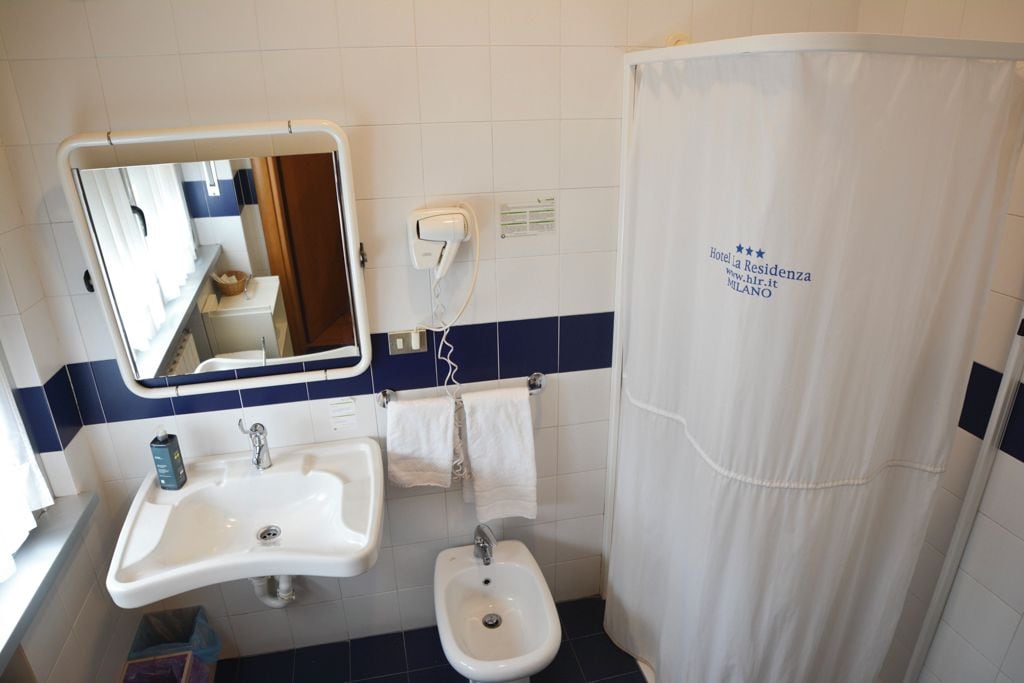 A bathroom with a sink, mirror, and shower curtain.