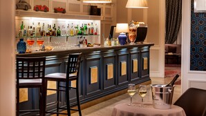 Una zona de bar con mostrador, taburetes y una mesa con una botella de champán.