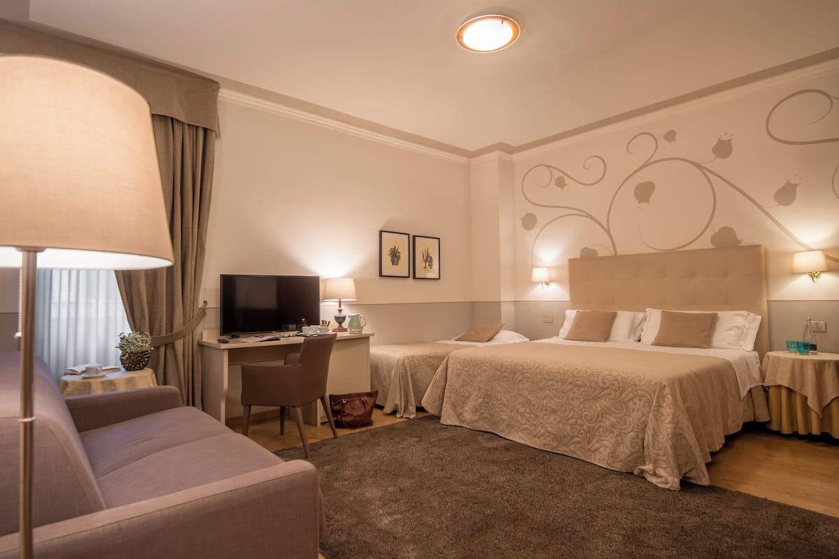 A hotel room with a bed, a desk, a television, and a sofa.