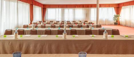Ein Konferenzraum mit Tischen, Stühlen und Namensschildern, ausgestattet mit Wasserspendern und Gläsern.