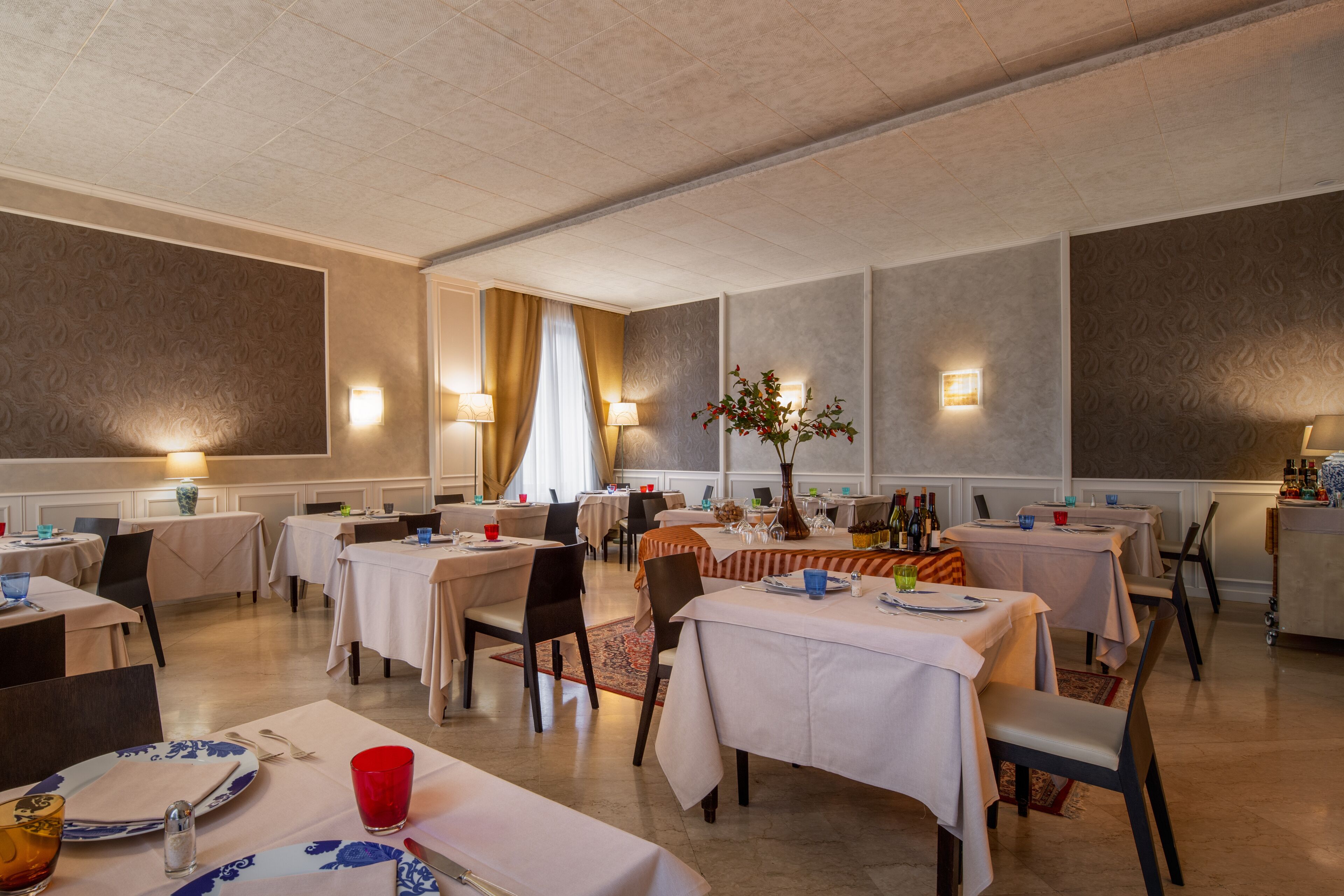 Un comedor con mesas dispuestas para comidas, iluminación ambiental y una decoración central.