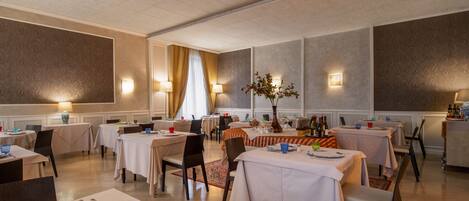 Un comedor con mesas dispuestas para comidas, iluminación ambiental y una decoración central.