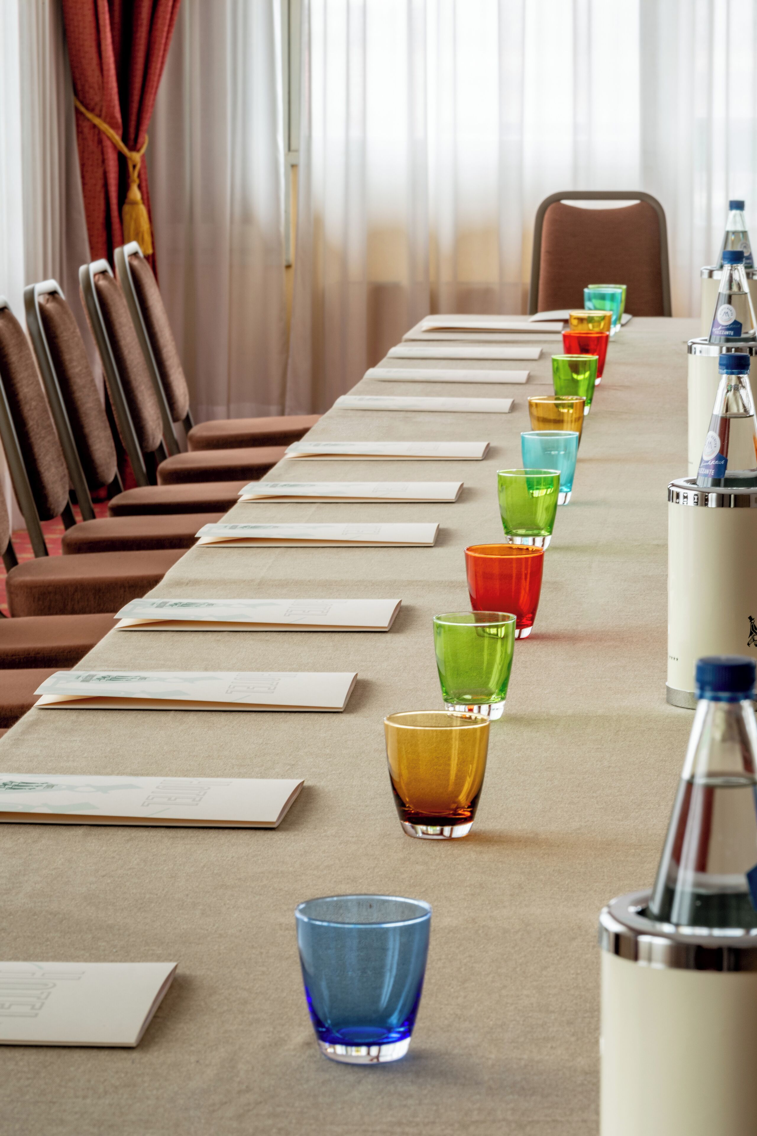 Une table de conférence avec des chaises, une bouteille d’eau et un verre.